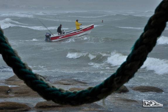 Barco sai na chuva e com mar agitado em Cabo Polonio, no litoral do Uruguai